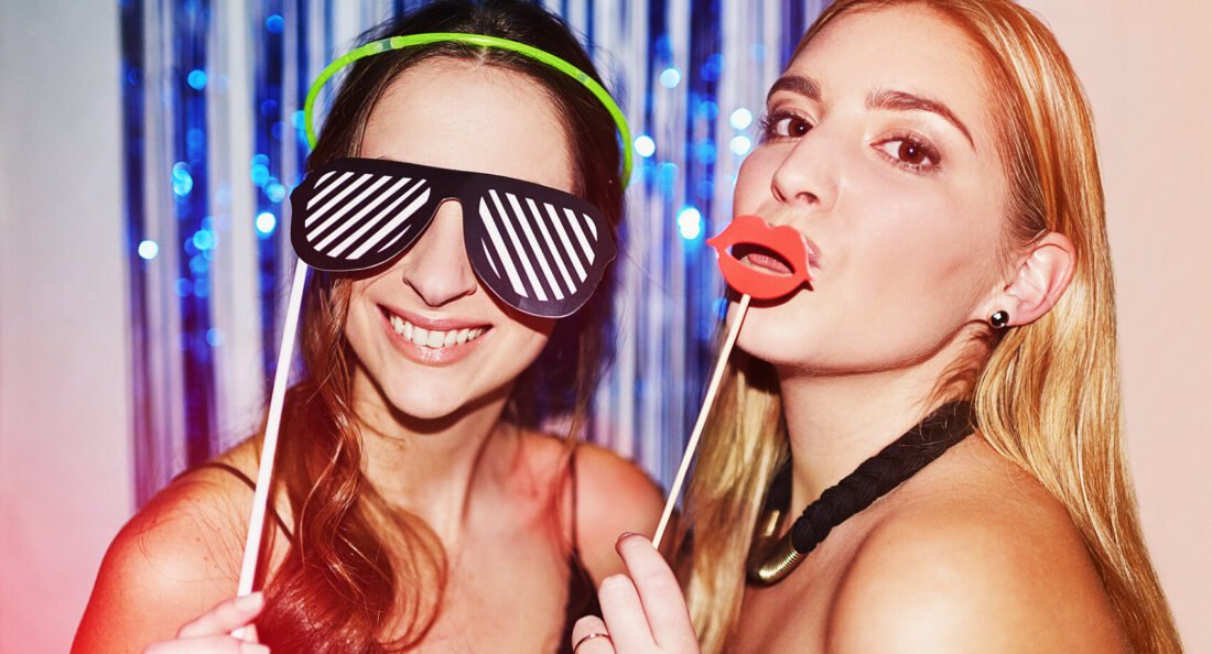 two women having fun with props in a photobooth